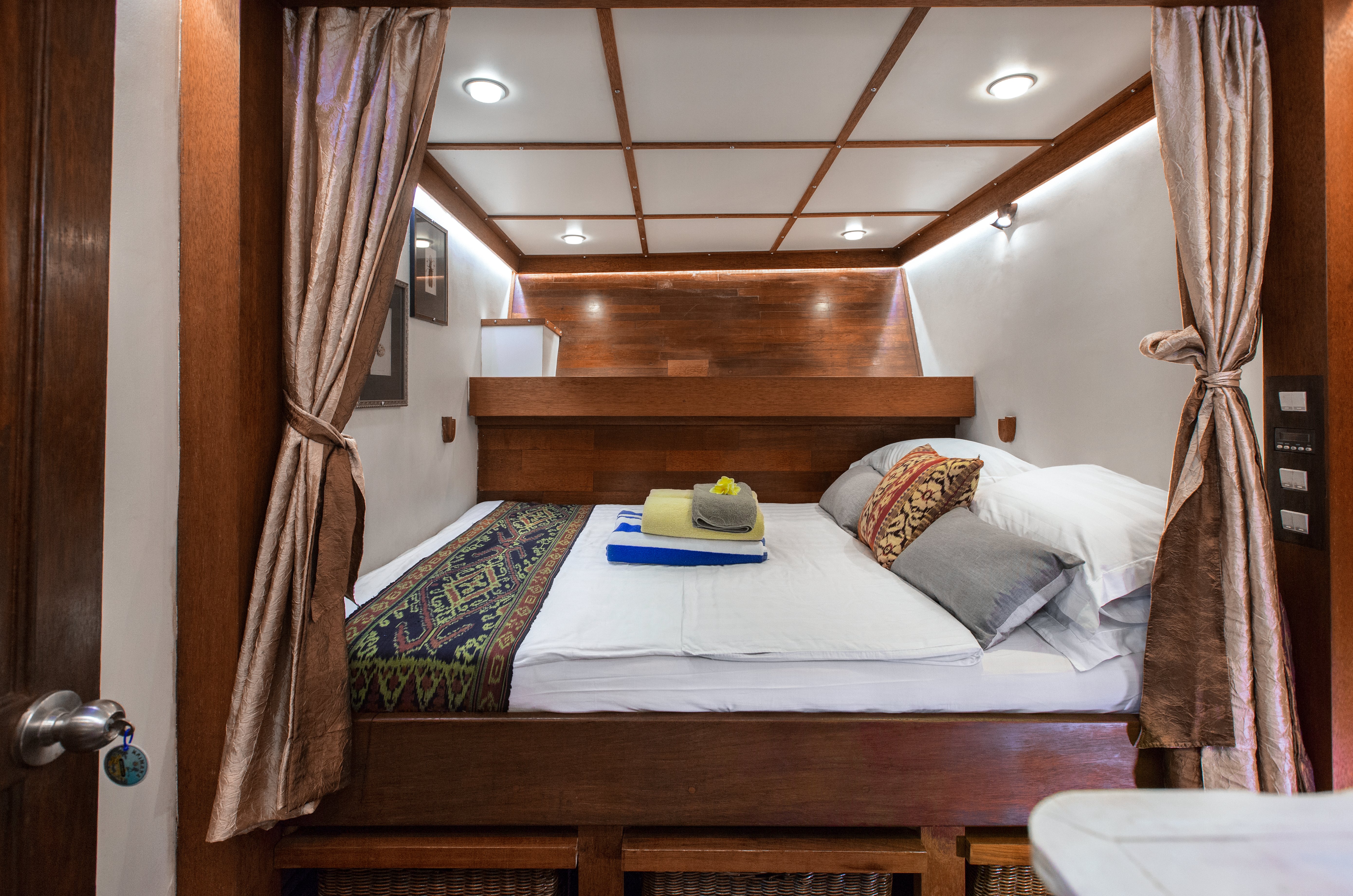 A double cabin on the SeaTrek cruise has wooden furnishings and a comfy bed.