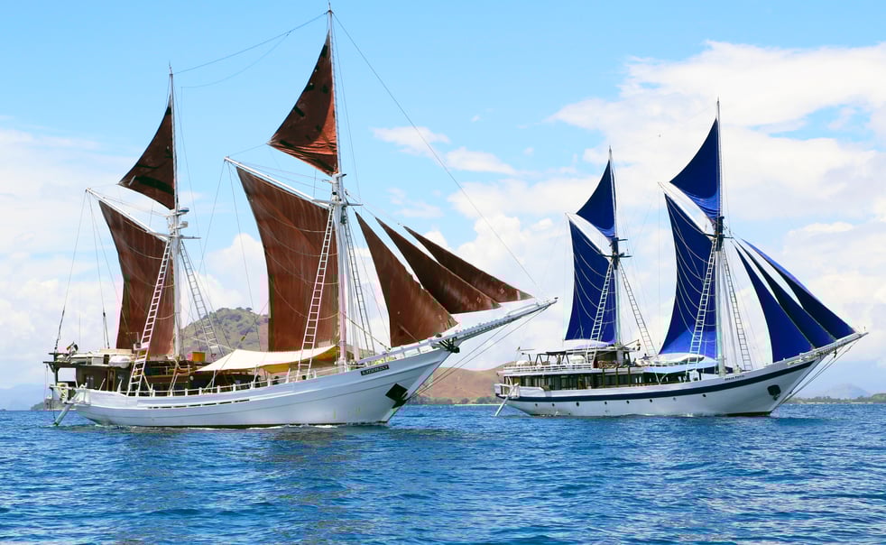Two traditional Indonesian boats float on the deep blue sea.