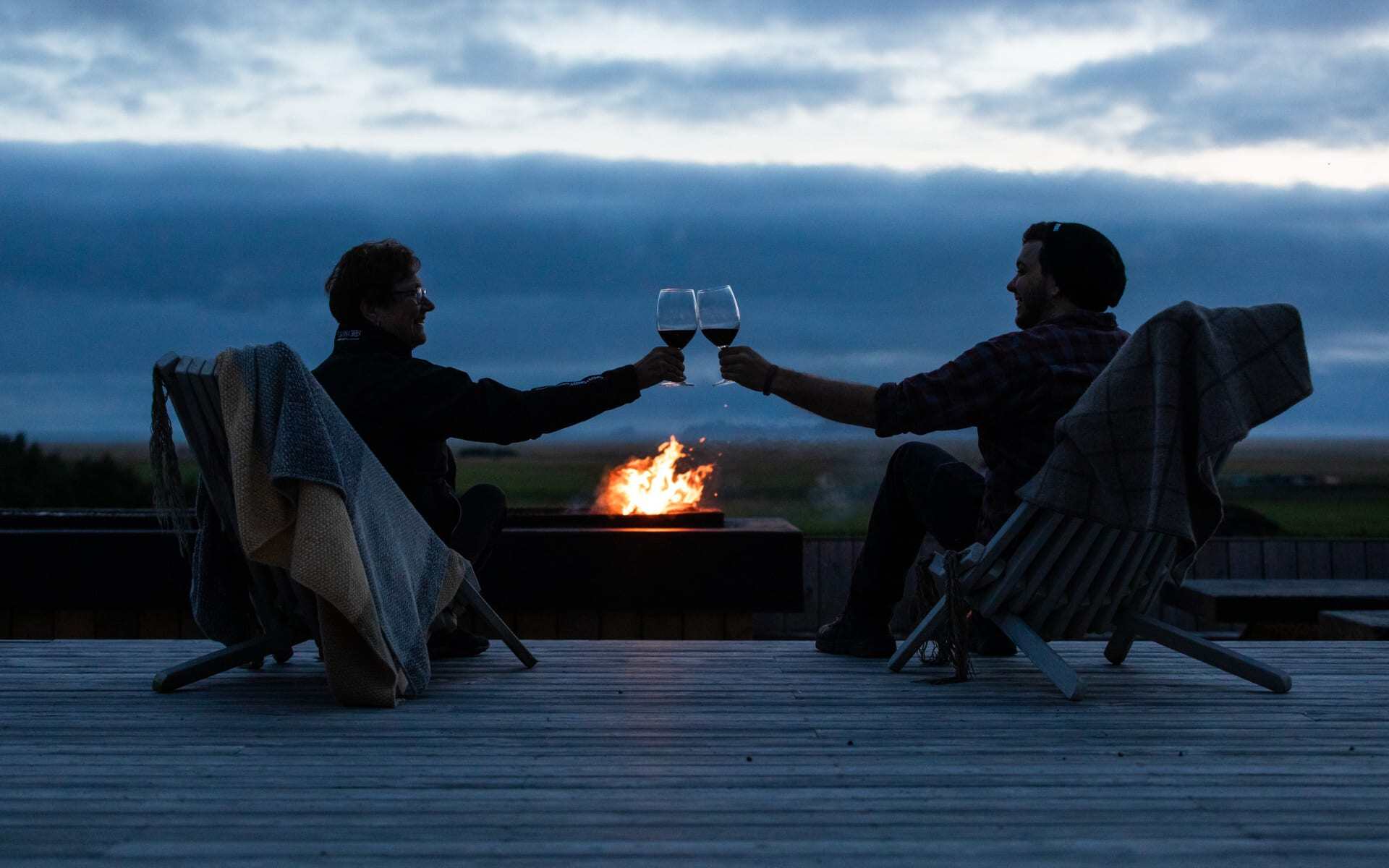 Two guests enjoy an evening glass of wine ahead of a campfire at Skalacot Manor.