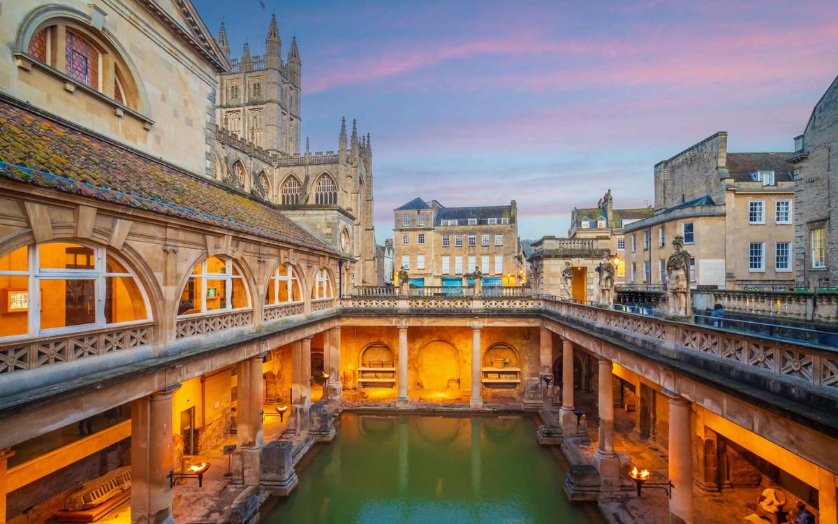 The roman baths have intricate stone architecture during sunset in Bath.