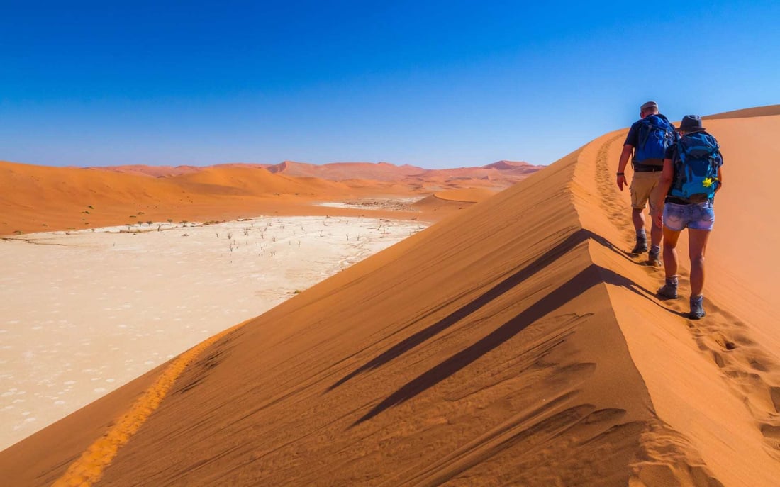 Two people hike in Sossusvlei in Namibia.