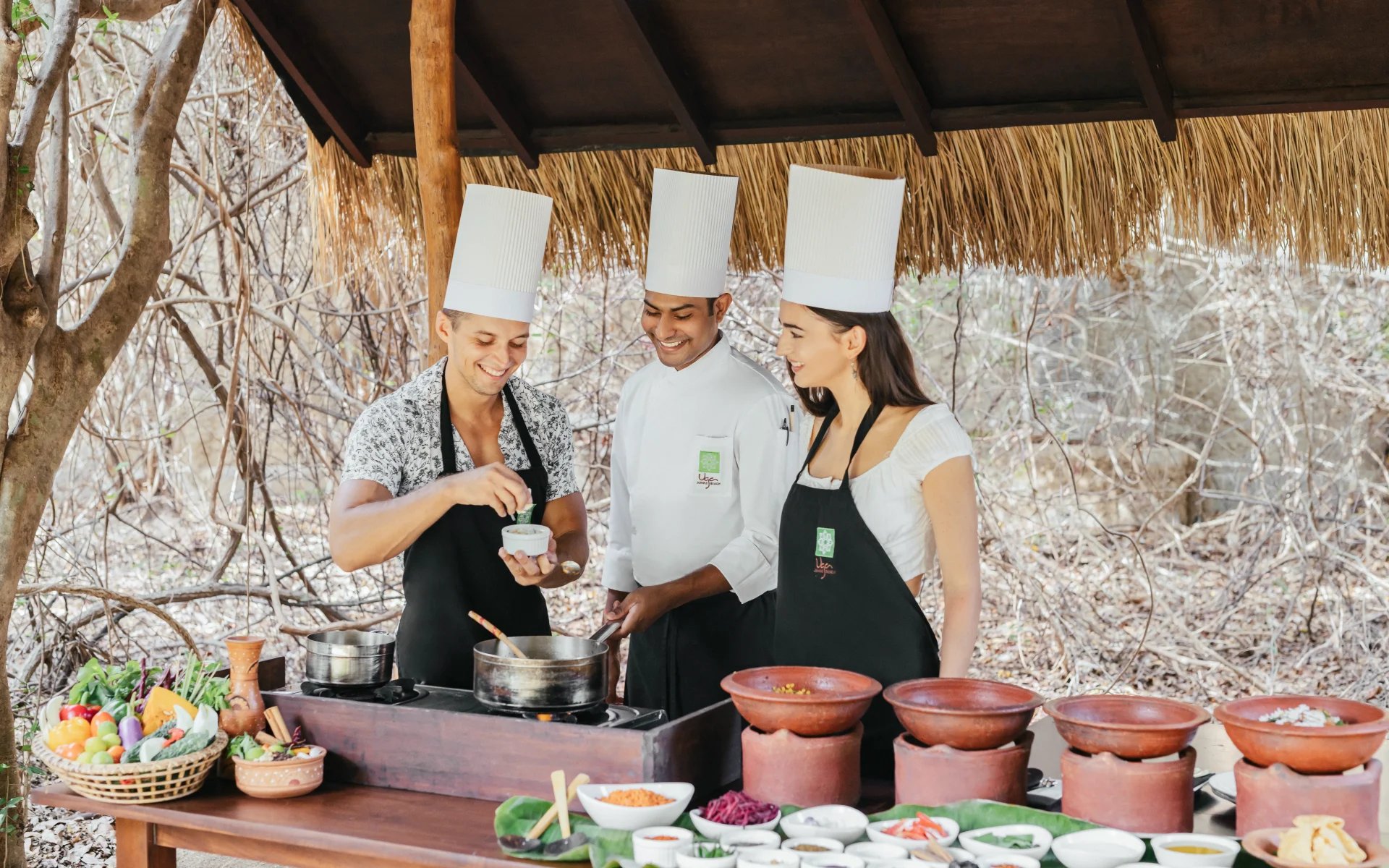 A couple is partaking in a cooking lesson with one of the hotel chefs.