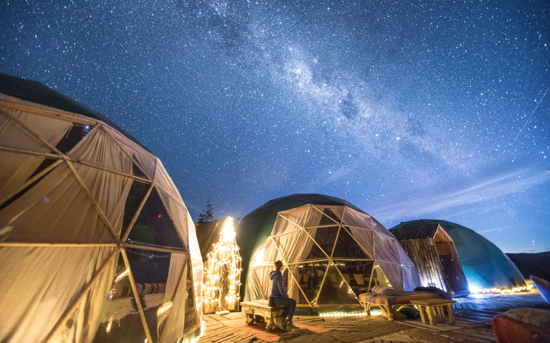 Three domes are illuminated with lights and sit under a starry night. 