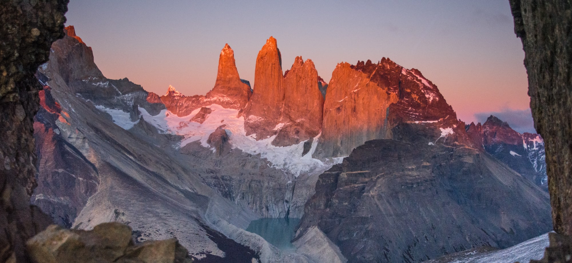 Mountain peaks are the colour of red, purple and orange as the sun sets. 