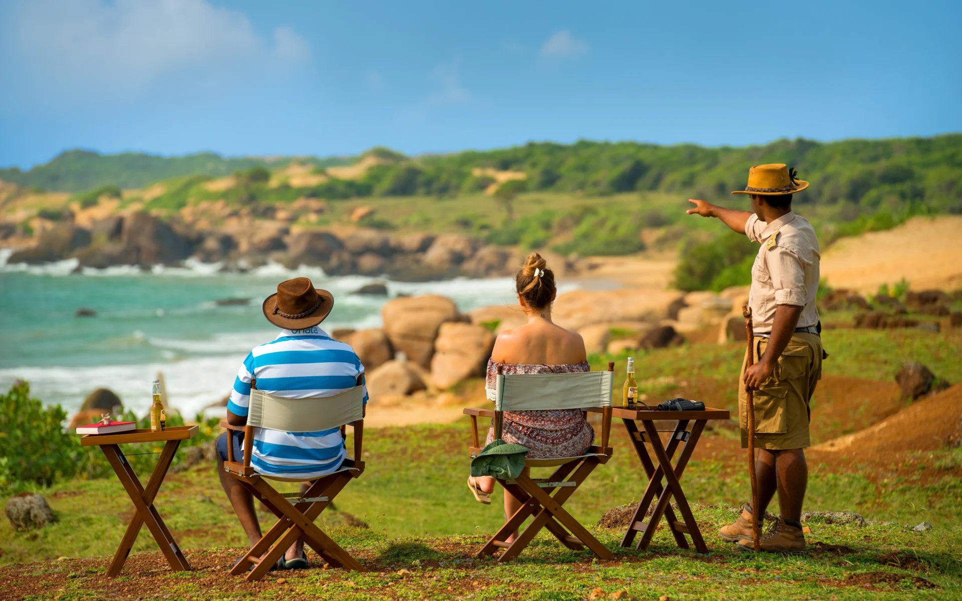 People are sitting on chairs overlooking the beach. 