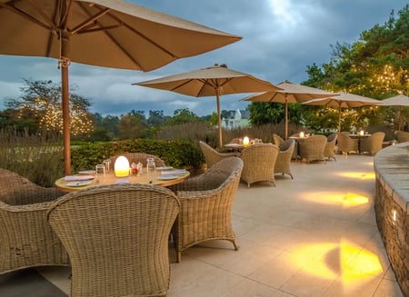 The outside seating area stretches around the outdoor pool. Wickered seats and wooden tables are covered by cream-coloured parasols.