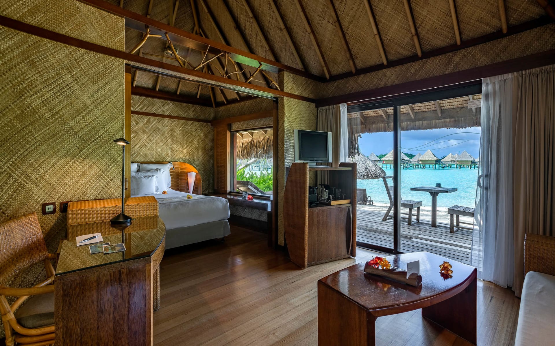 A double bed has flowers on it and the room opens to a balcony. 