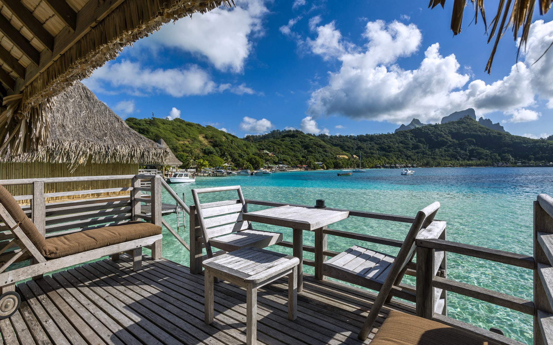 A wooden deck with seating is situated over water.