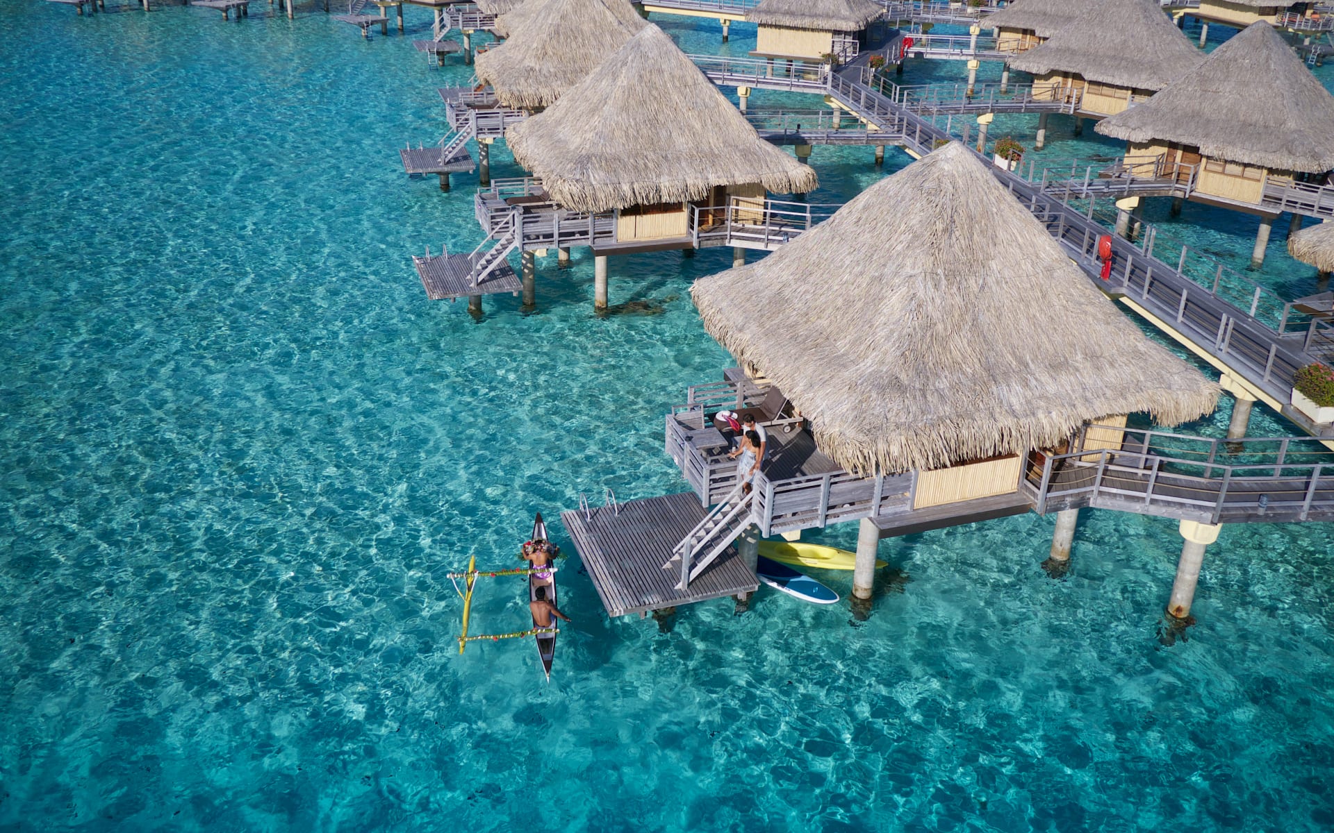 A couple are climbing up the ladder of a private water villa. 