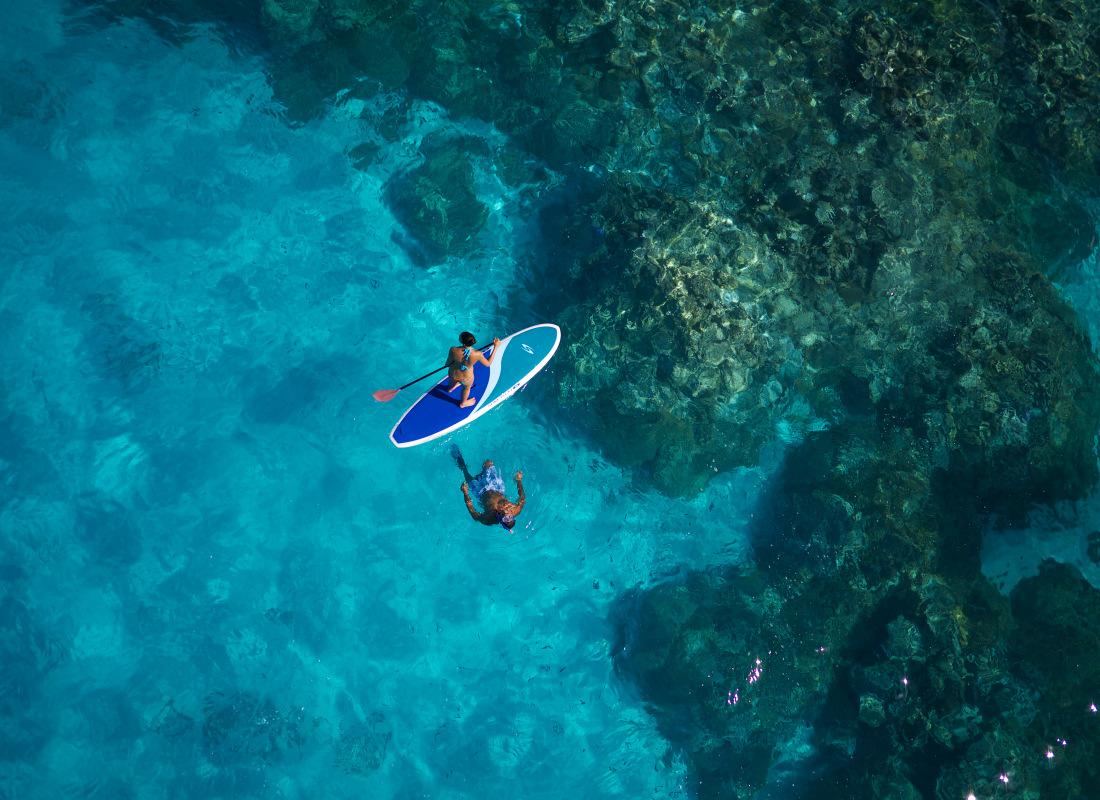 A couple are stand-up paddle boarding. 