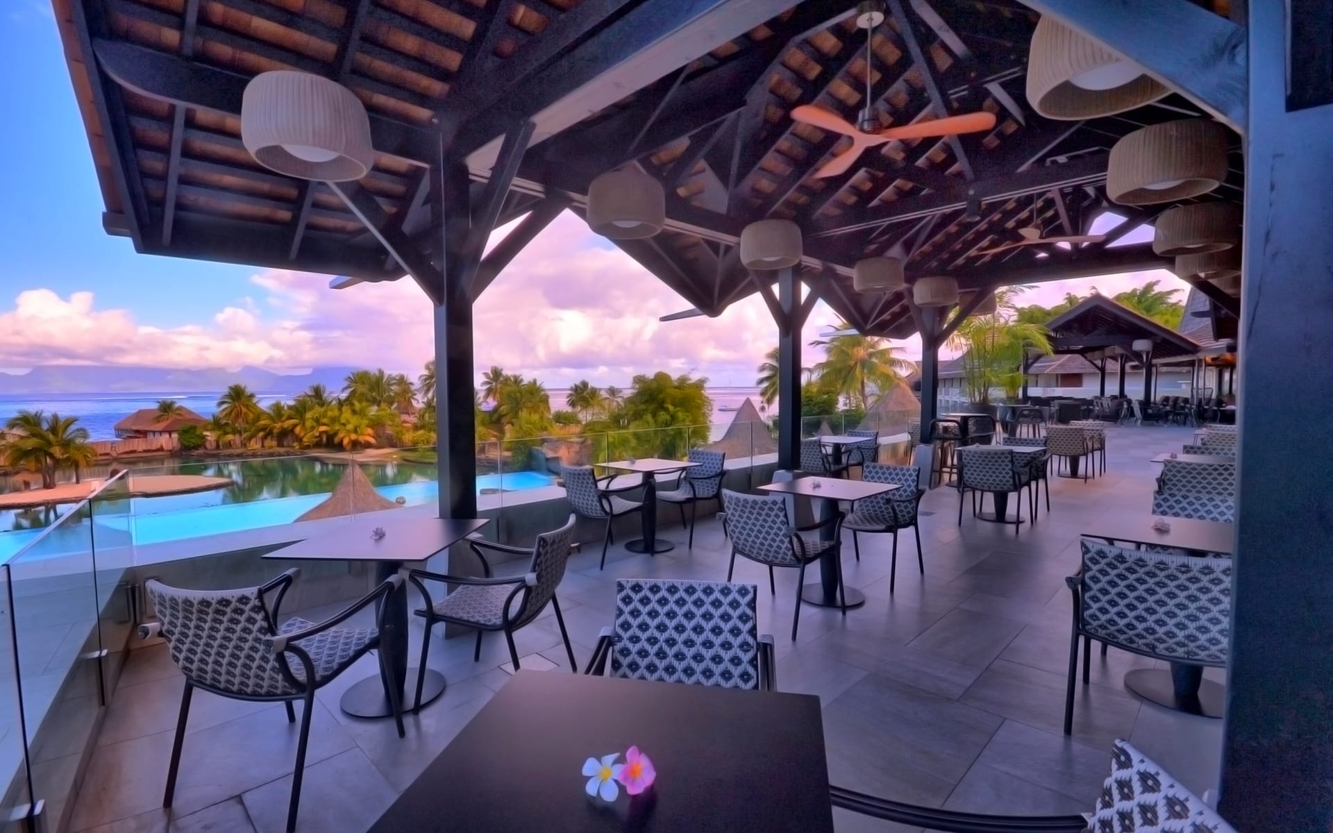 The lobby bar has seating and tables overlooking a blue pool.