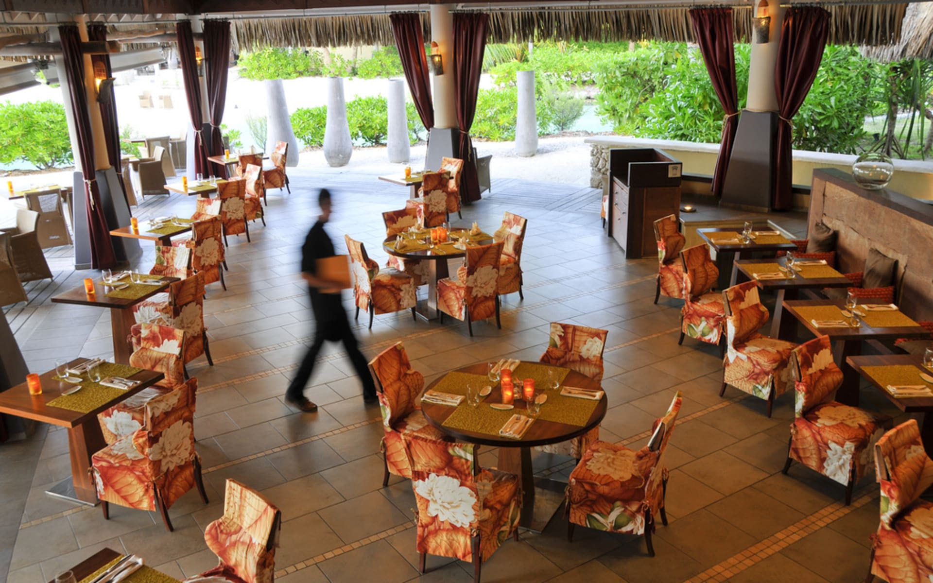 The restaurant has tables and orange chairs. 