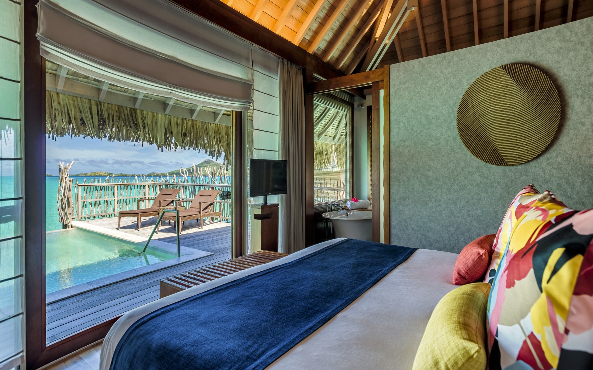 A double bedroom has a floor-to-ceiling door opening to the deck and pool.