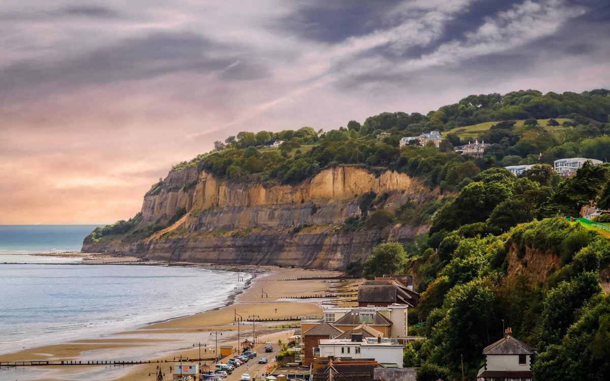 Huge cliffs face the sea on a golden beach in the Isle of Wight.