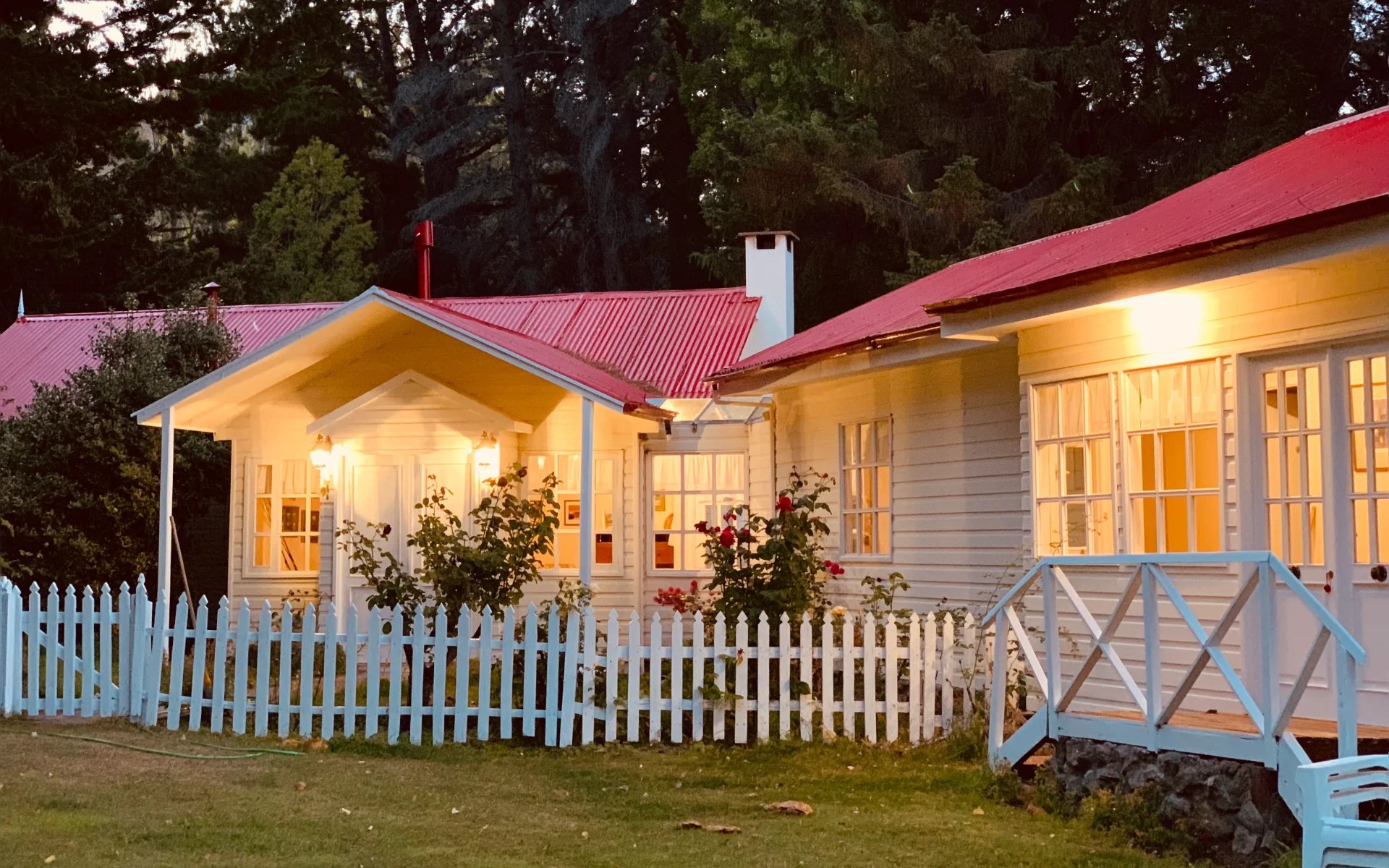 The porches of the private bedrooms lead directly to the estancia's gardens. They are lit with warm lighting and fronted by white picket fences.