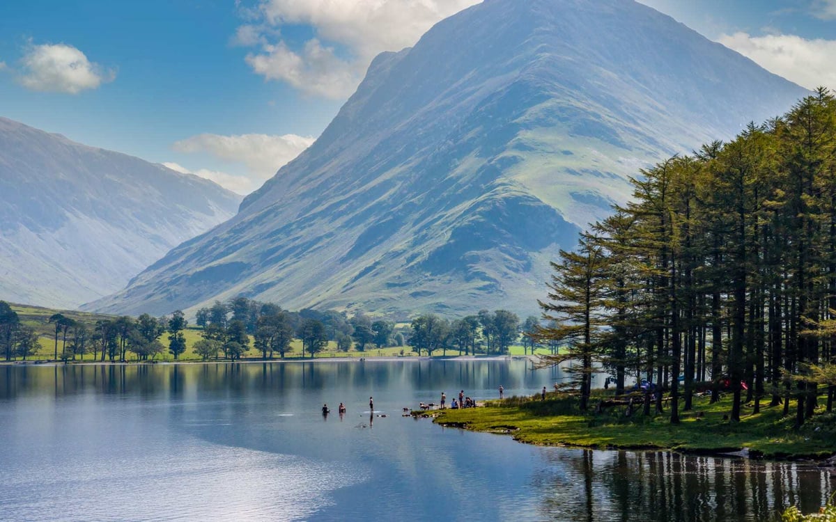 People relax on the banks of a huge lake in Buttermere in the Lake District.