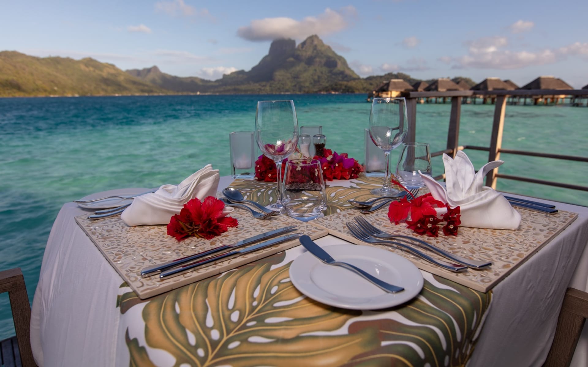 A dining table sits on the edge of the ocean. 