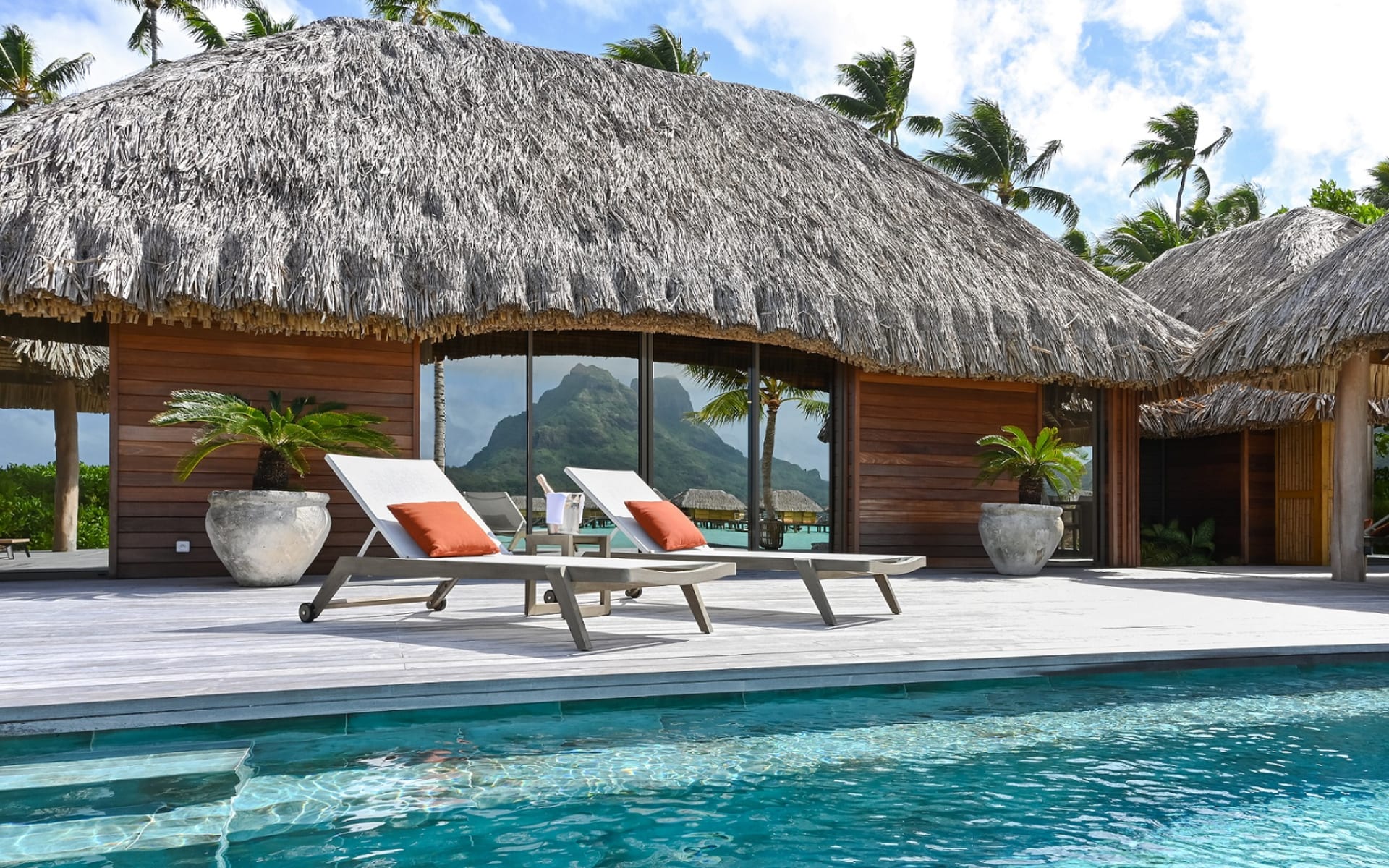 Two sun loungers in front of a swimming pool. 