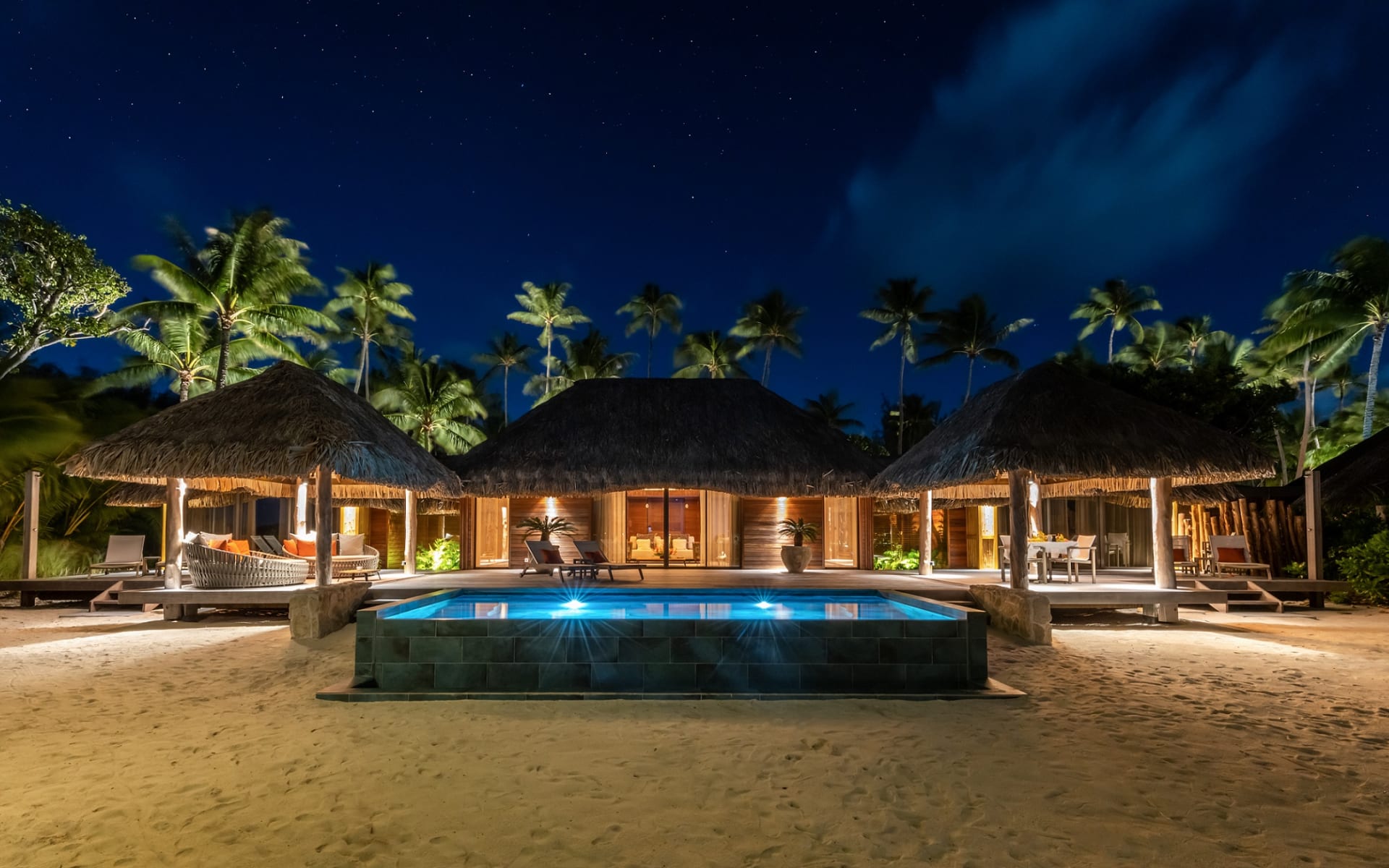 A villa is lit up with lamps in the evening. 