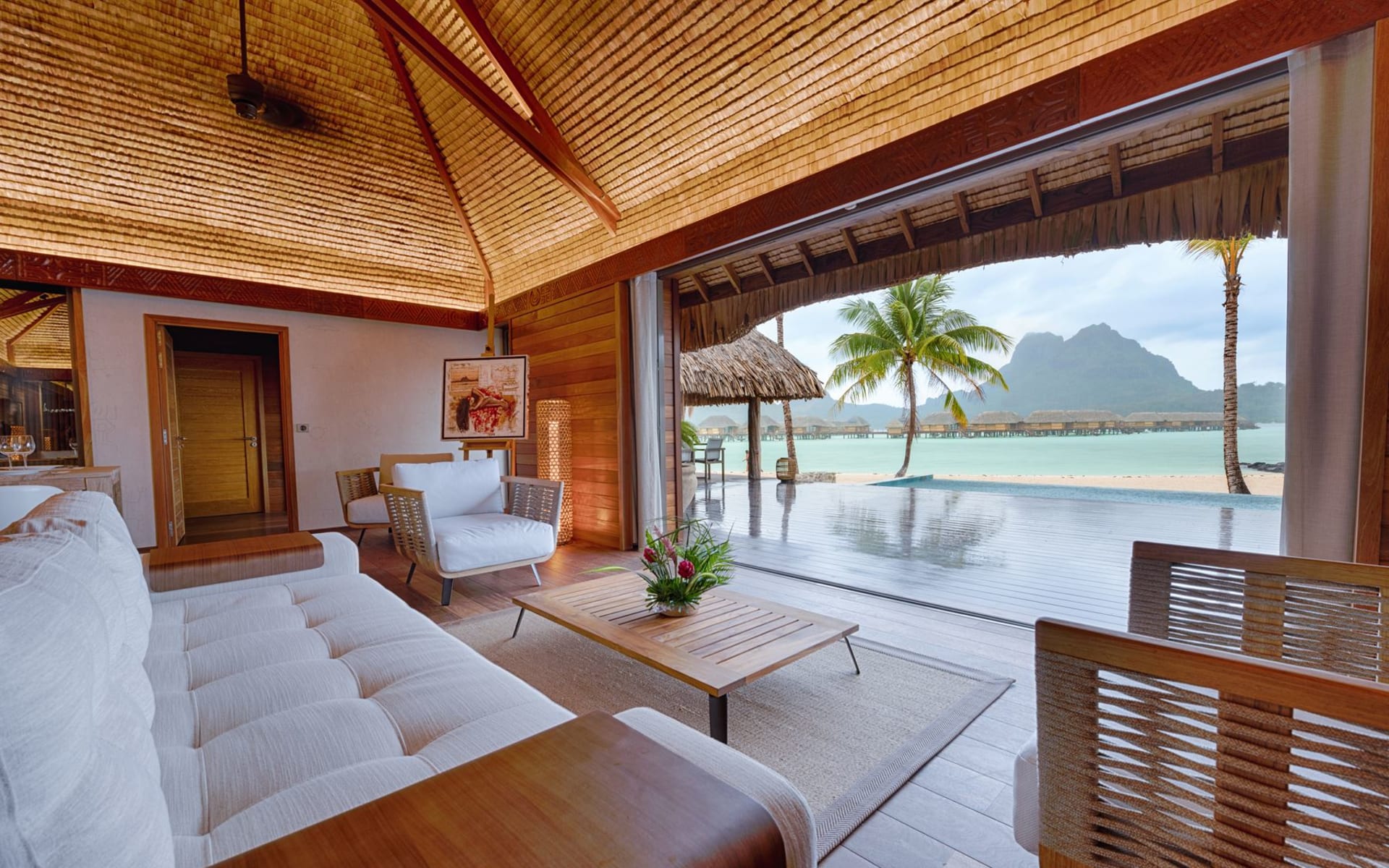 A living room has an open-plan design and connects to the outdoor swimming pool.