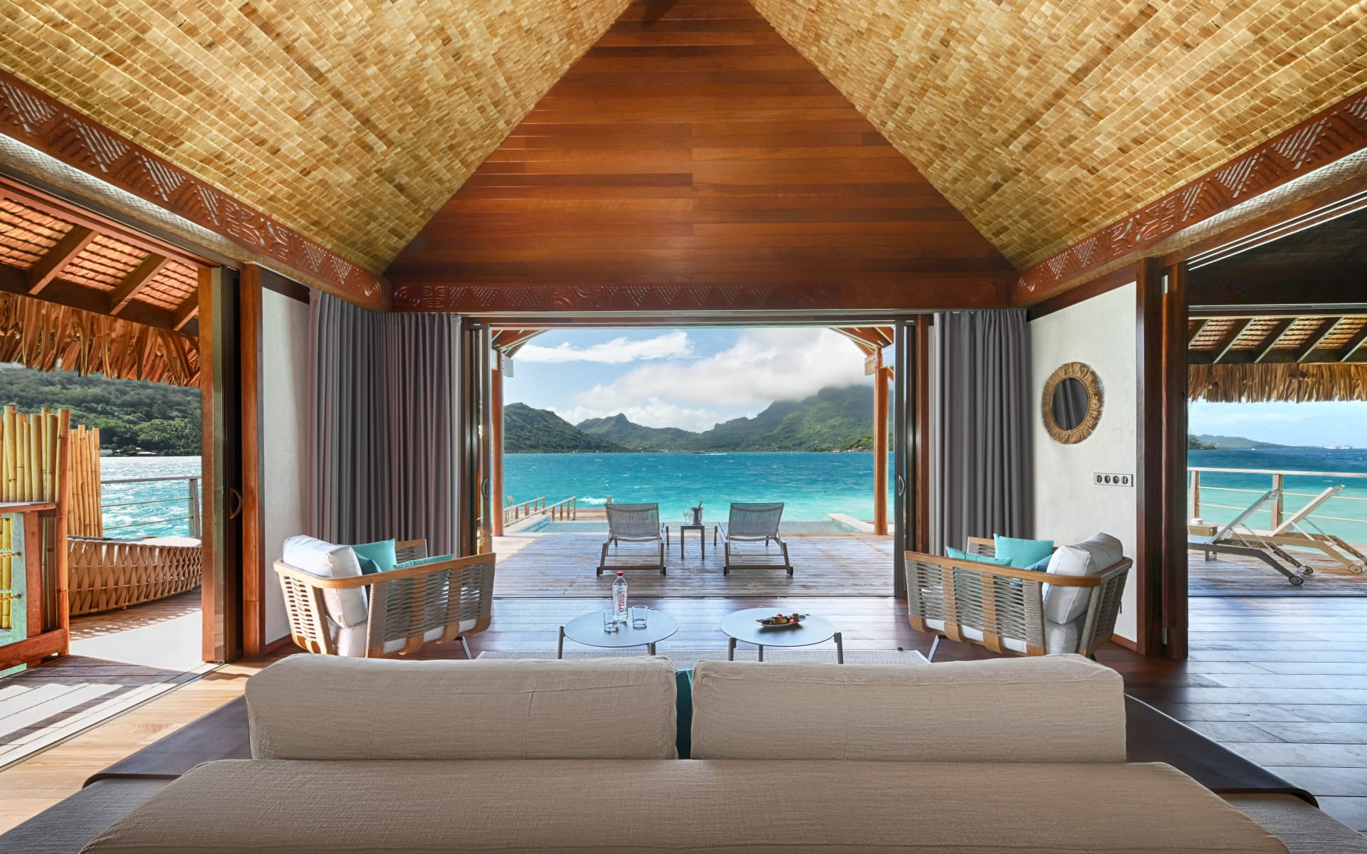A living room opens to a deck with sun loungers and an infinity pool.