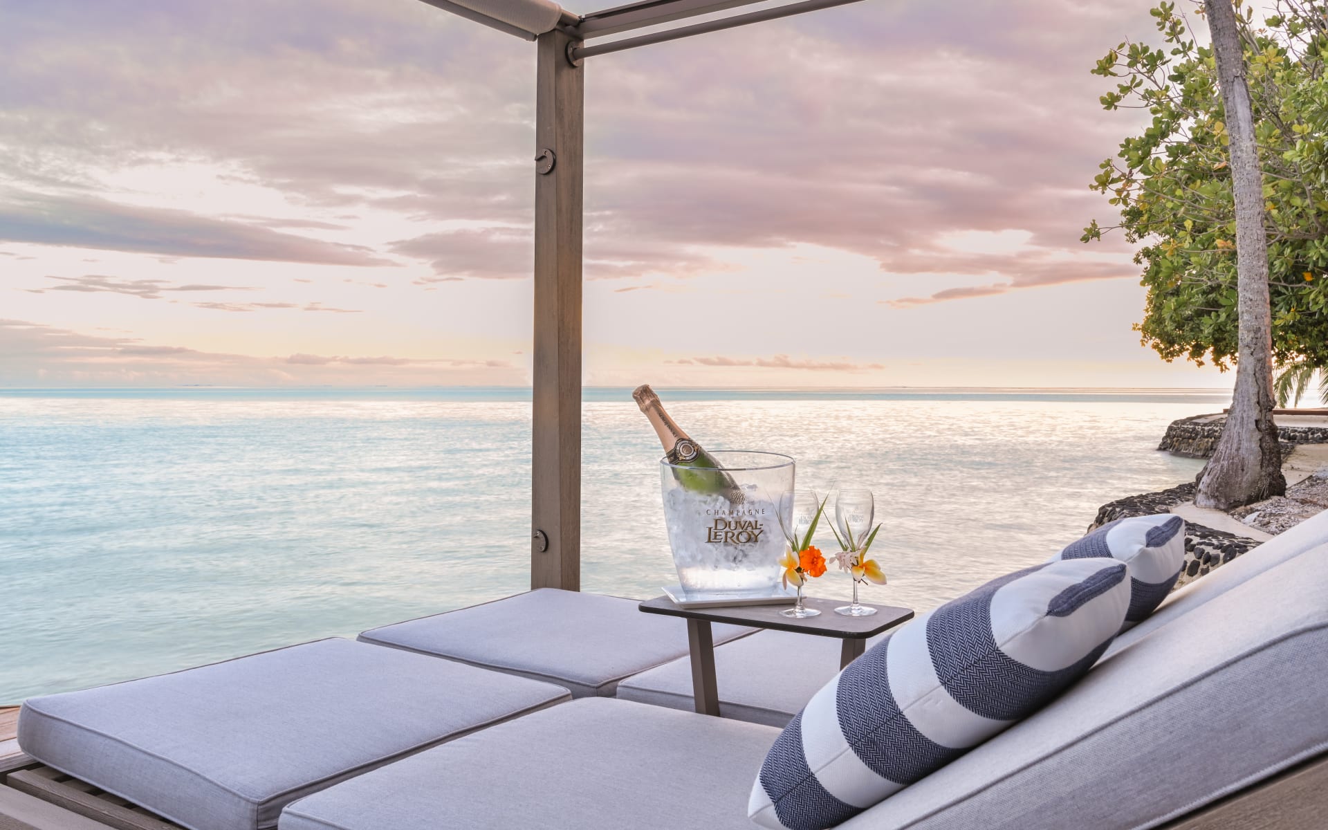 Champagne beach longue chairs looking over sunset ocean