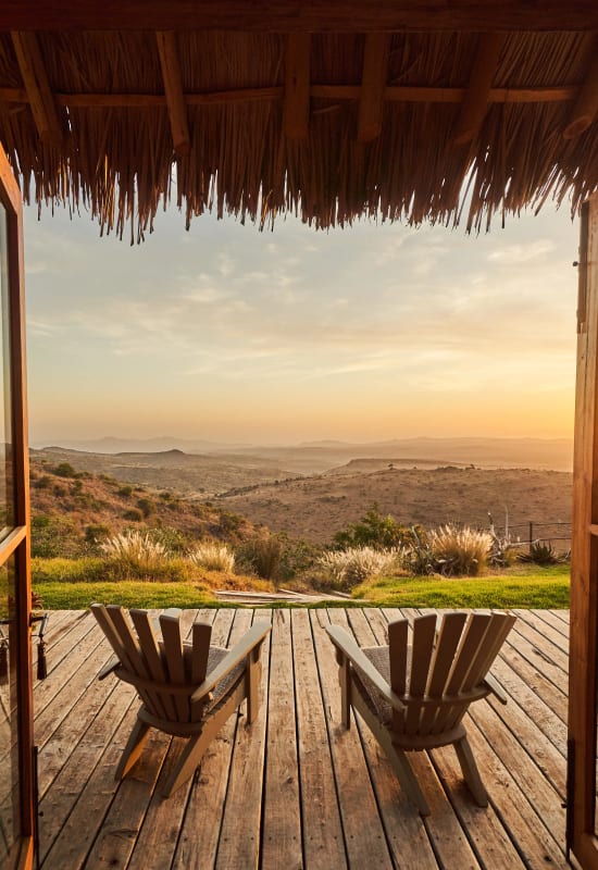 Two deck chairs are placed on one of the room's private verandas, overlooking a mountainous scenery during the late afternoon.