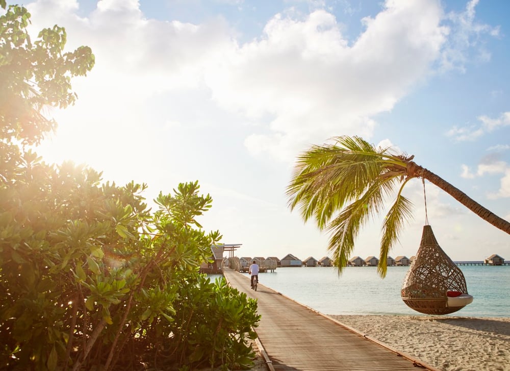 A man rides a bike on decking at Lux South Ari Atoll.