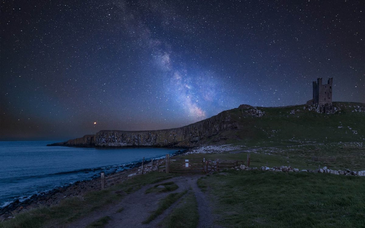 The sky is deep blue and full of stars on the Northumberland coast.