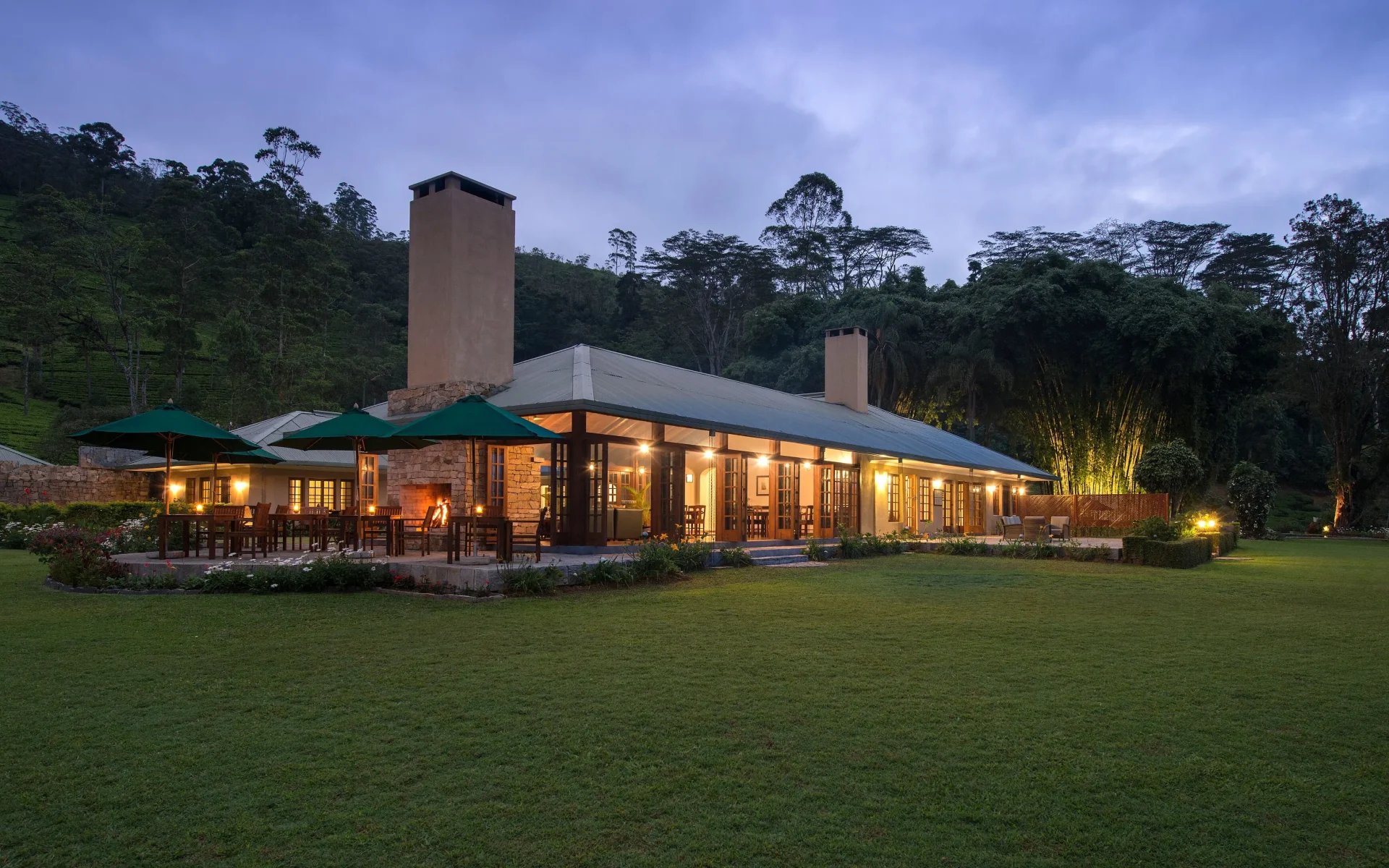 The Norwood Bungalow is warmly lit, with low-slung architecture, surrounded by lush grass.