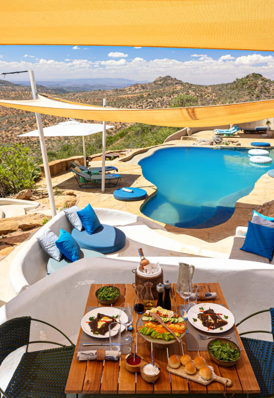A table is draped with a colourful food spread made up of fruits, vegetables, baked foods and seasonings.