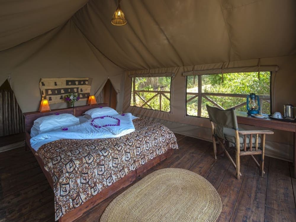 A double bed with a desk, chair and rug in a tent