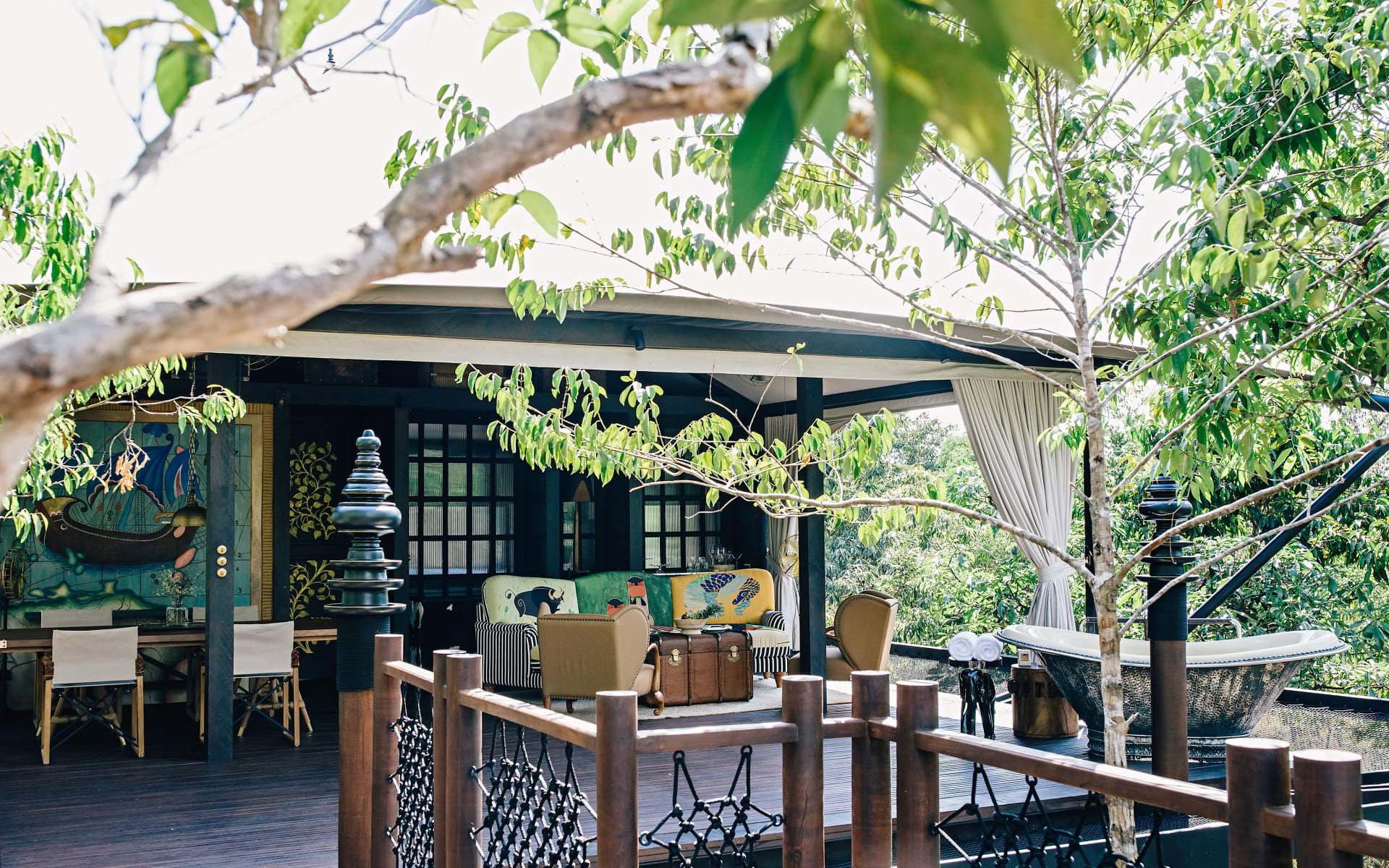 Shinta Mani Wild has a deck with cosy sofas and armchairs surrounded by trees. 