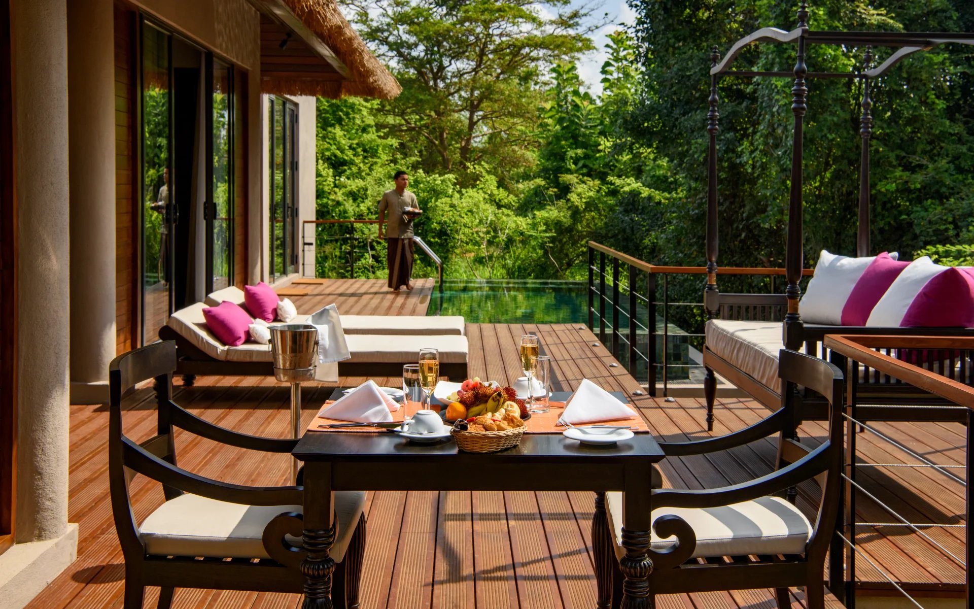 A private dining set-up is on the private veranda of one of the villas in the resort. There are two glasses of champagne.