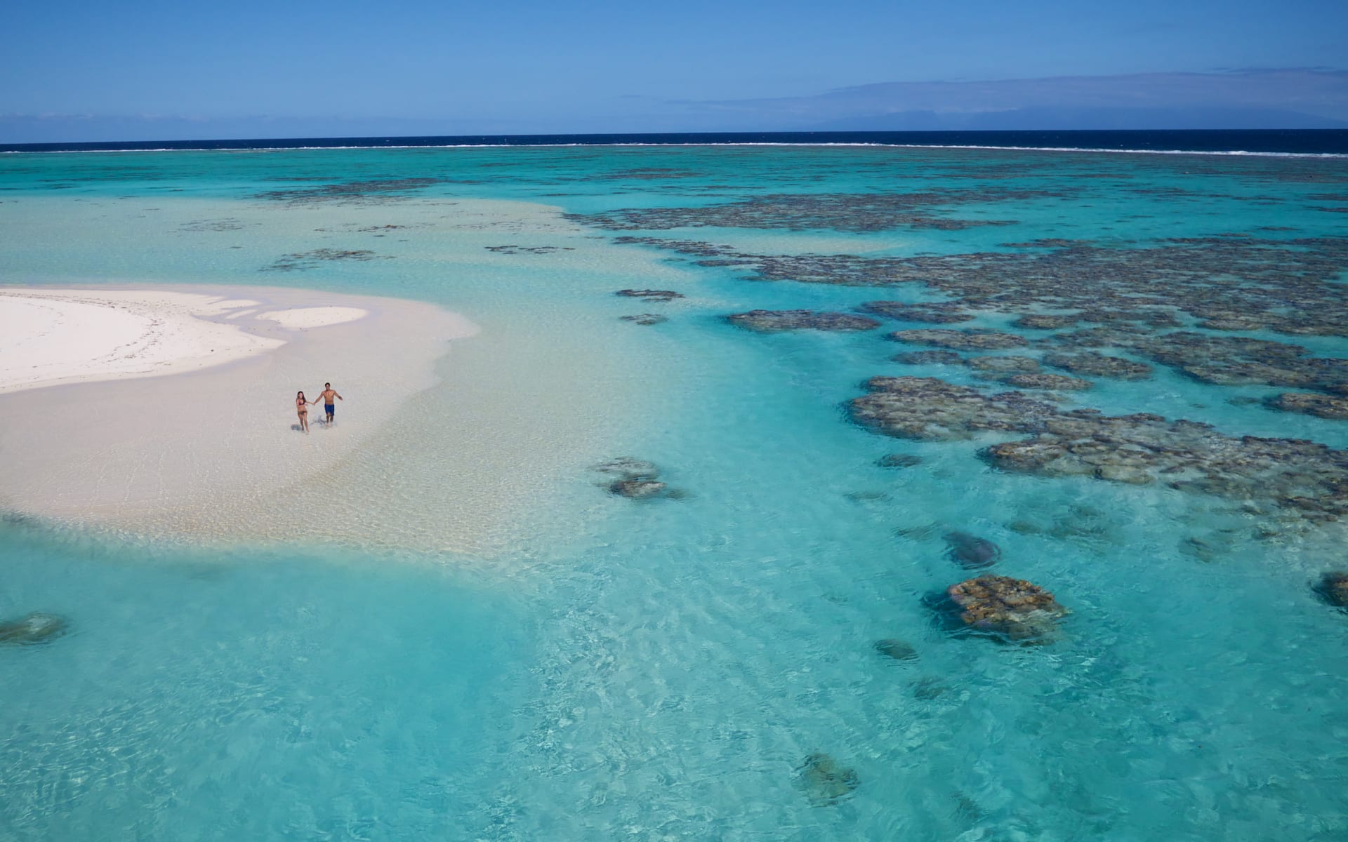 Ariel view of couple on beach and having a dip in the ocean