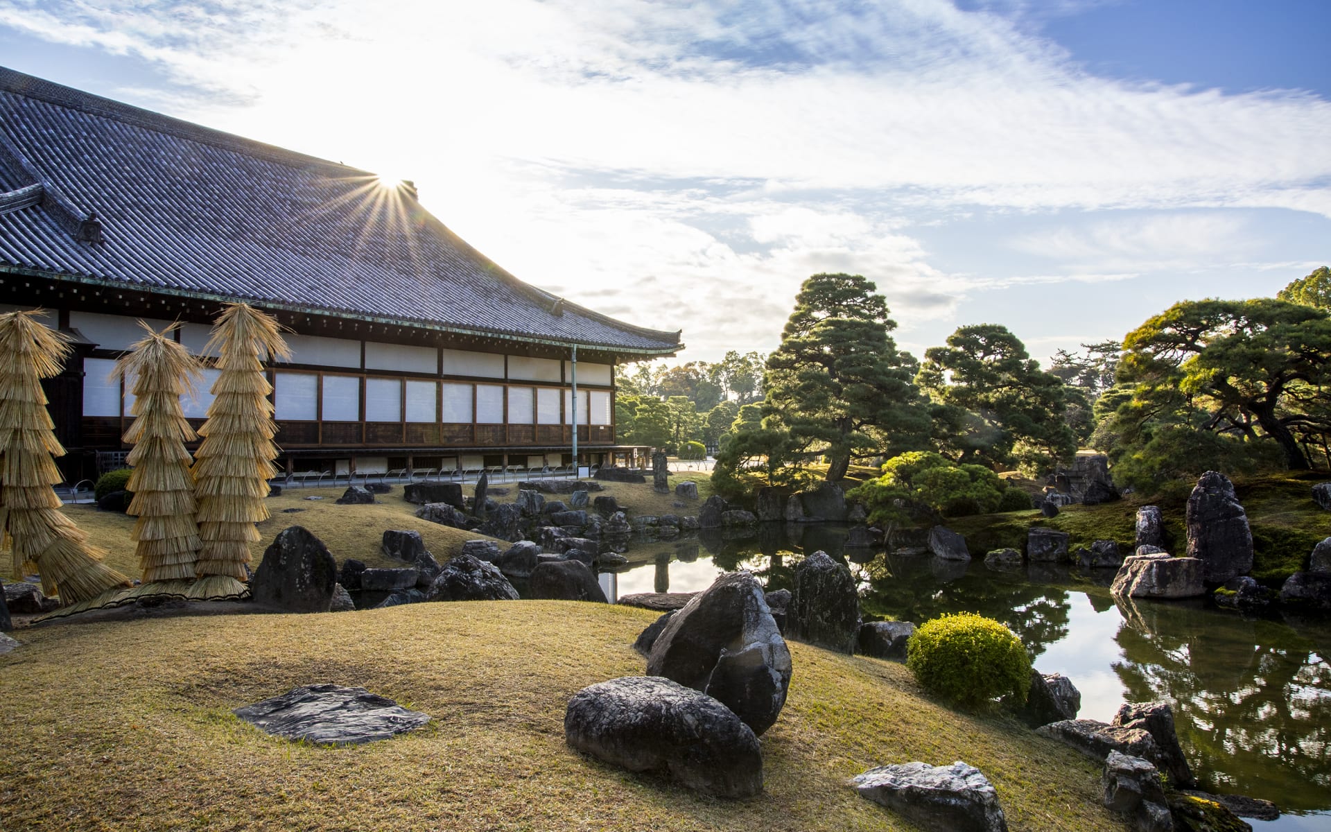 The Mitsui Hotel's garden has a pond with stones, trees and a blue sky. 