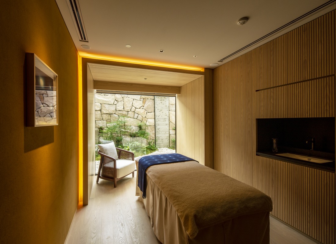 The Mitsui Hotel treatment room is a wooden space with orange lighting, a single table and chair.