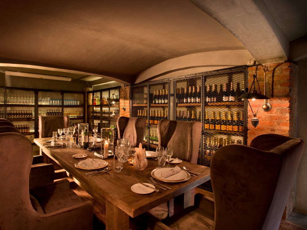 A long dining table with shelves of wine surrounding it.