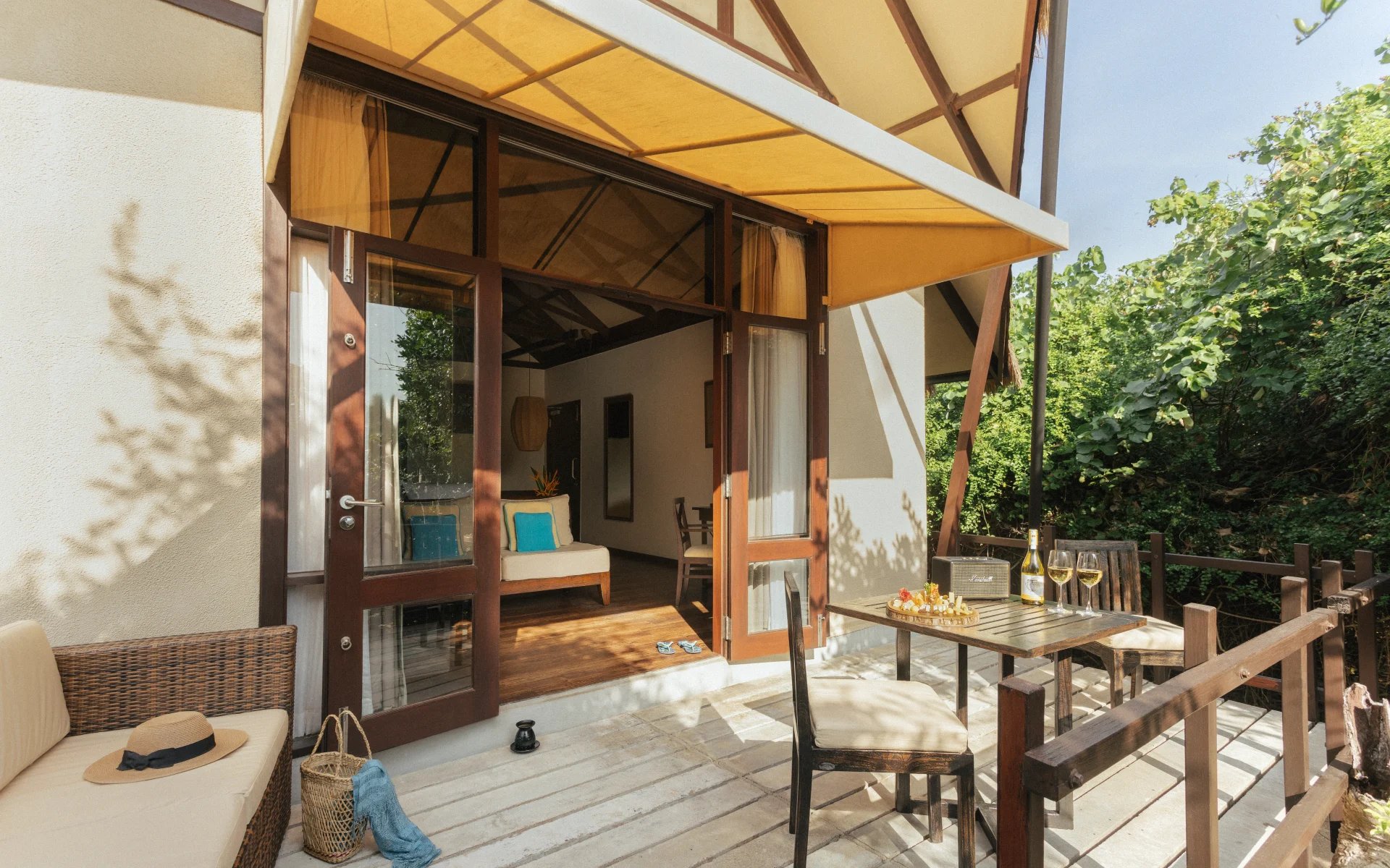 A private verandas attached to one of the Beach Cabins. A bottle of white wine sits on the outdoor dining area and the sun is shining.