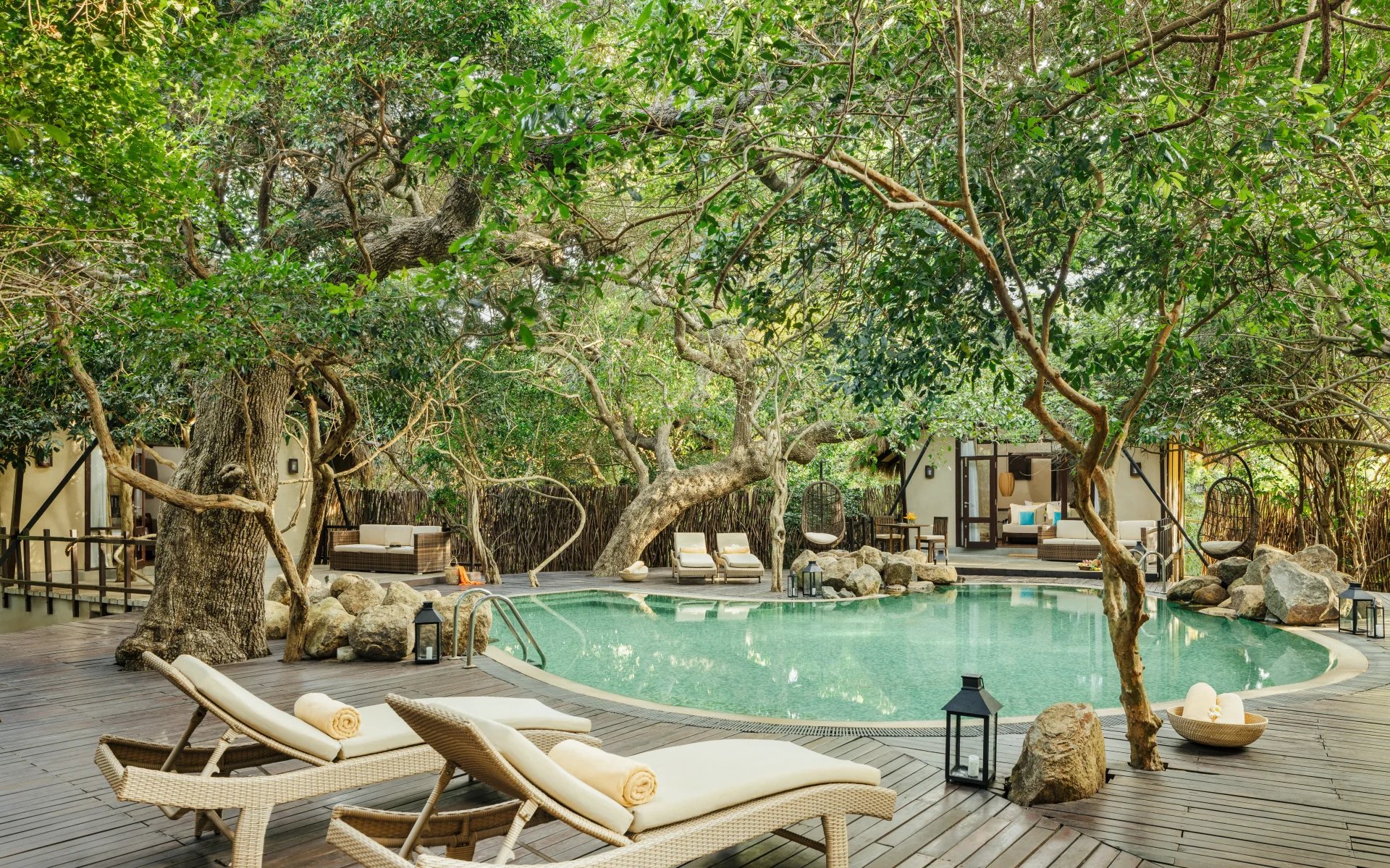 The outdoor spa pool is framed by a wooden sun deck and enshrouded by trees.