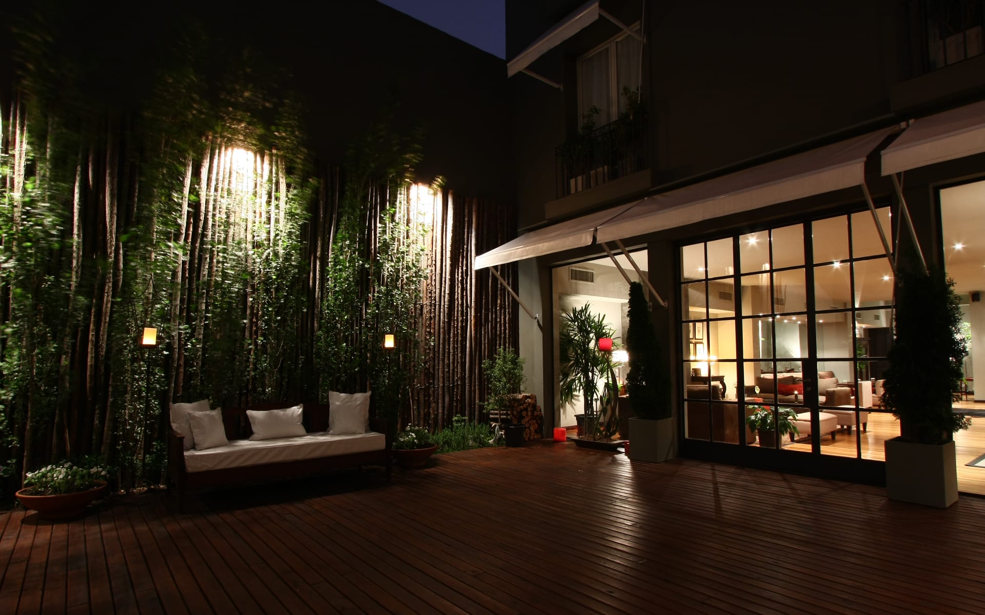 The patio at Legado Mitico is wooden and surrounded by tall walls that have plants climbing up them, and there is an outdoor seating area.