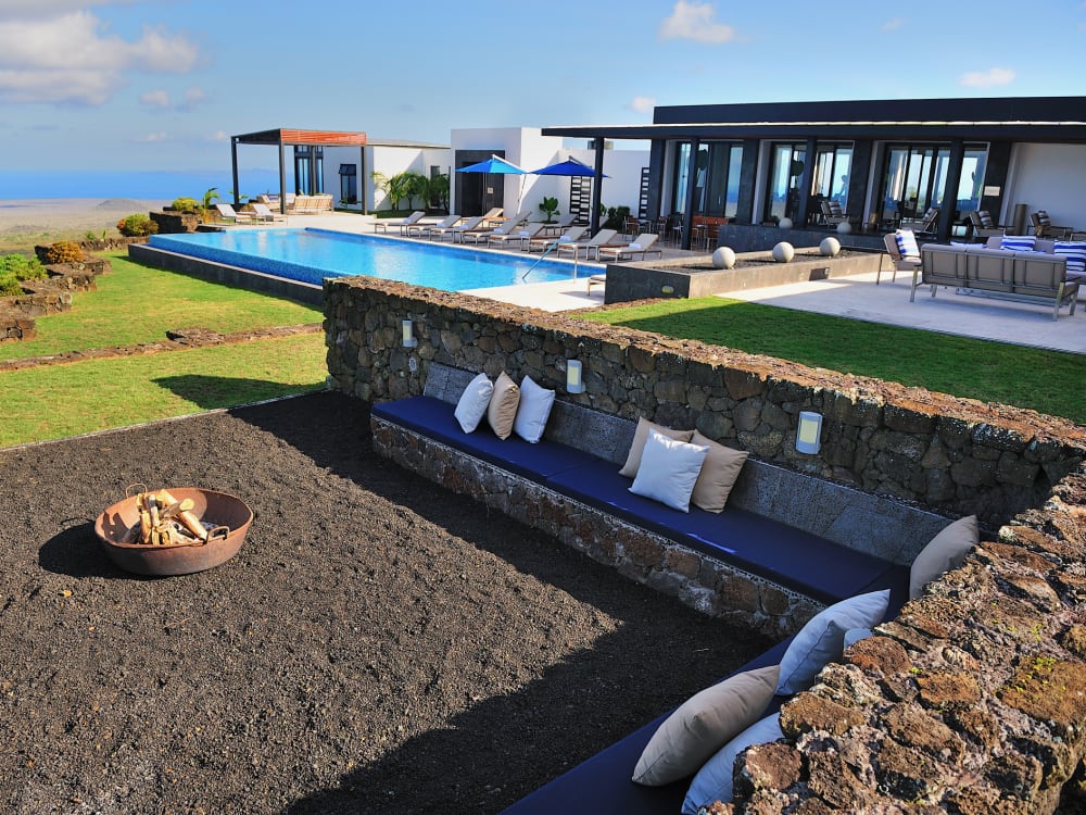 A fire pit at Pikaia Lodge overlooking a pool and sun chairs