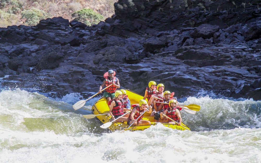A group of friends enjoy whitewater rapids on a trip in Victoria Falls.