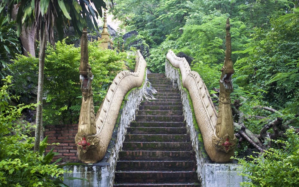 A narrow staircase covered in moss leads up Mount Phousi.