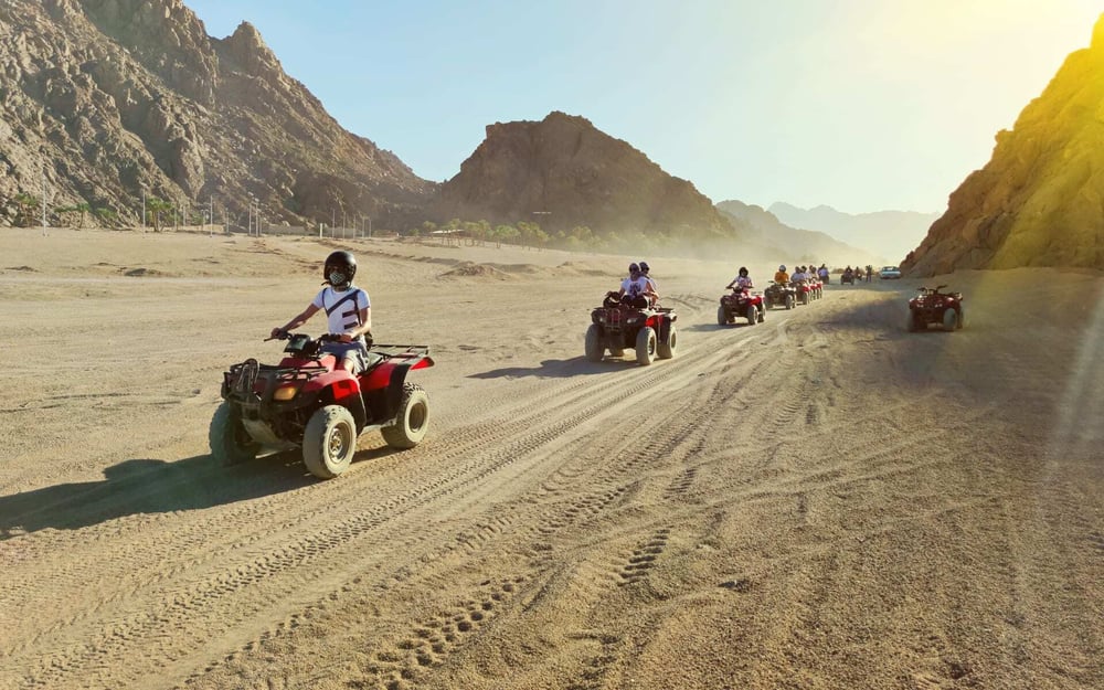 A group of friends enjoy quad-biking in the desert on a group tour.