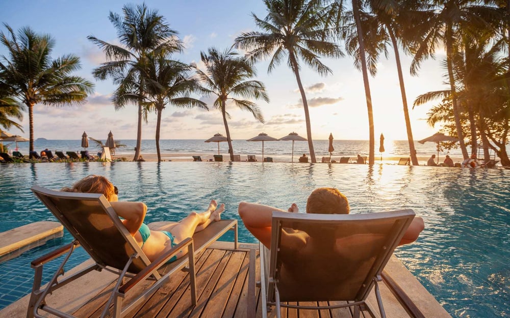 A couple relax by the pool in the Maldives.
