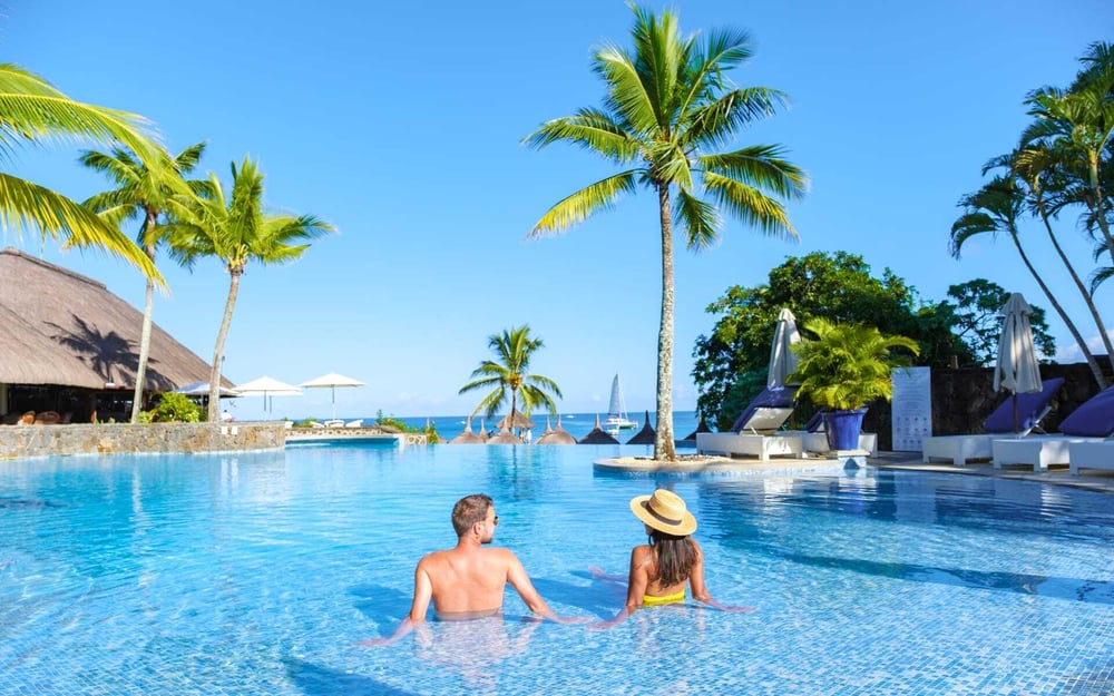 a couple relax in a swimming pool in a luxury hotel in Mauritius.