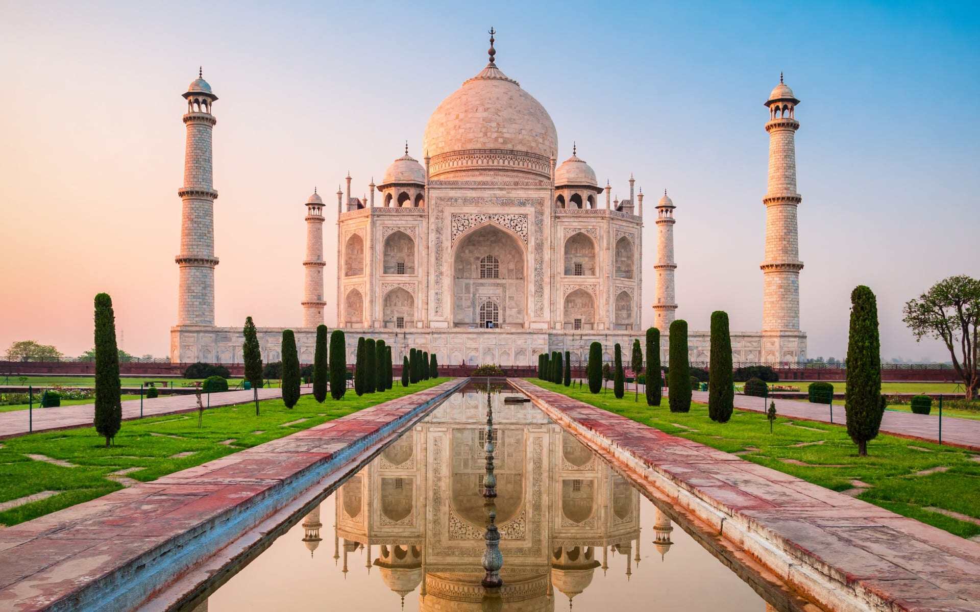 The Taj Mahal looks beautiful ahead of its reflection pool during sunrise.