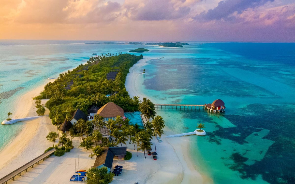 This Maldives island has jungle and white beaches during sunset.