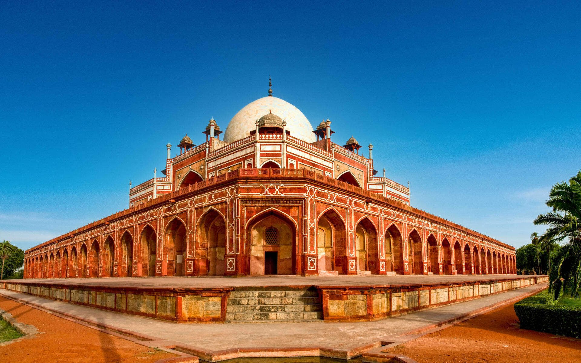 Humayun's Tomb has a rustic, red sandstone exterior with many archways. 